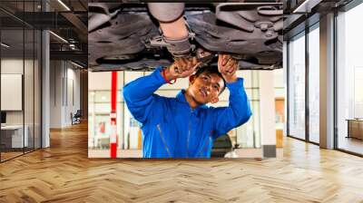 Mechanic standing and fixing under a lifted car with copy space Wall mural