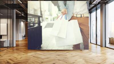 Shopaholic man walking on commercial street with a lot of shopping bags Wall mural