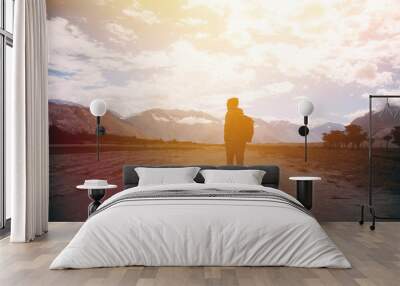 silhouette of male traveler with backpack walking against the sunlight in mountain highland area. Wall mural