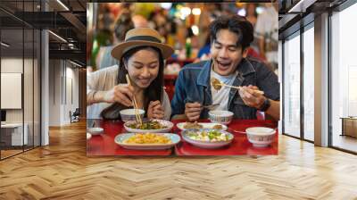 Young Asian couple traveler tourists eating Thai street food together in China town night market in Bangkok in Thailand - people traveling enjoying food culture concept Wall mural