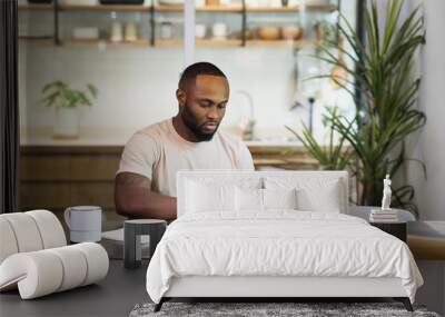 Young business black african american man working from home on table with notebook computer laptop Wall mural