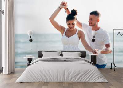 Young happy and joyful Caucasian adult romantic couple dancing on the tropical summer beach - honeymoon travel and leisure concept Wall mural