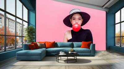 Young sweet and attractive woman in luxury fashion lifestyle blowing chewing bubblegum isolated over pink background. Wall mural