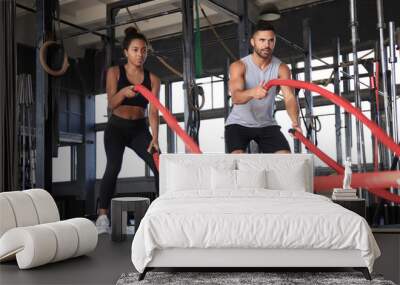 Athletic young couple with battle rope doing exercise in functional training fitness gym. Wall mural