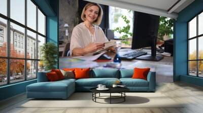 Attractive middle aged woman working at office, using contemporary desktop computer. Wall mural