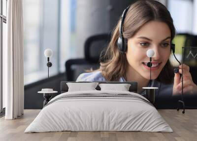 Beautiful smiling call center worker in headphones is working at modern office Wall mural