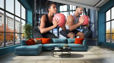 Beautiful young sports couple is working out with medicine ball in gym. Wall mural