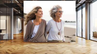 Ederly mother and her adult daughter enjoying walk along beach Wall mural