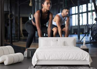 Fit and muscular couple focused on lifting a dumbbell during an exercise class in a gym. Wall mural