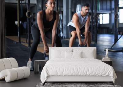 Fit and muscular couple focused on lifting a dumbbell during an exercise class in a gym. Wall mural