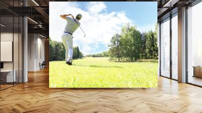 Golfer hits an fairway shot towards the club house. Wall mural