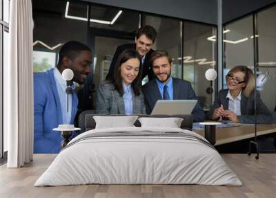 Group of happy diverse male and female business people in formal gathered around laptop computer in bright office. Wall mural