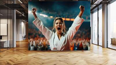 karate woman in a white uniform rejoices after winning a tournament in a stadium filled with spectators Wall mural