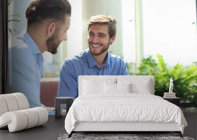 Mature businessman using a digital tablet to discuss information with a younger colleague in a modern business office. Wall mural