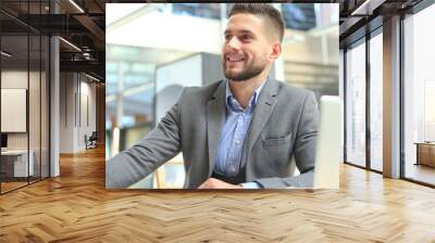 Portrait of young man sitting at his desk in the office. Wall mural