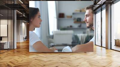 Side view of a couple talking sitting on a couch and looking each other at home. Wall mural