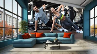 Strong man and woman holding dumbbells in plank position at the gym. Wall mural