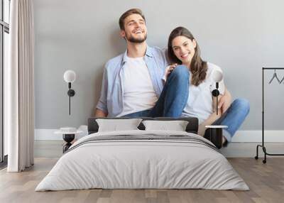 The happy couple sitting on the background of the gray wall. Wall mural