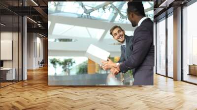 Two multinational young businessmen discussing business at meeting in office. Wall mural