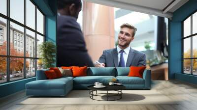 Two multinational young businessmen in suit in the office sign the contract. Wall mural