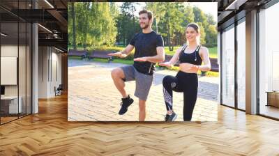 Young couple doing exercise together while working out outdoors in park. Wall mural