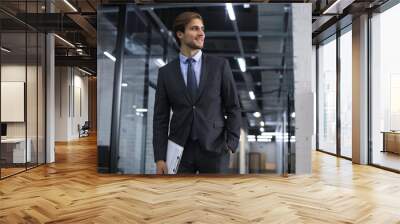 Young handsome businessman smiling in an office environment Wall mural