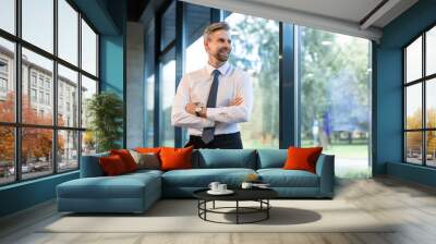 Young handsome businessman smiling in an office environment Wall mural