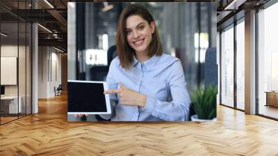 Young happy business woman showing blank tablet computer screen in office. Wall mural