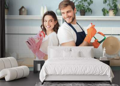 Young happy couple is having fun while doing cleaning at home. Wall mural