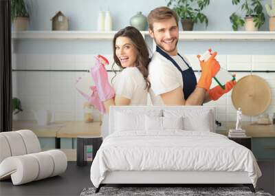 Young happy couple is having fun while doing cleaning at home. Wall mural