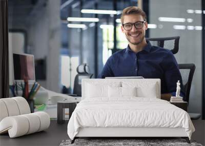 Young modern business man working using digital tablet while sitting in the office. Wall mural