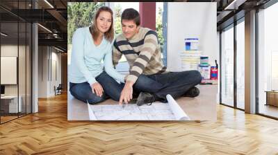 couple sitting on the floor with blueprint of their new house Wall mural