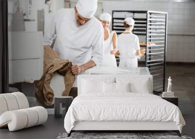 Mature Male Baker Pouring Flour In Kneading Machine Wall mural