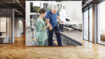 Physiotherapist Standing By Patient Walking Between Parallel Bar Wall mural