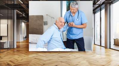 Senior Man Being Assisted By Male Caretaker In Bedroom Wall mural