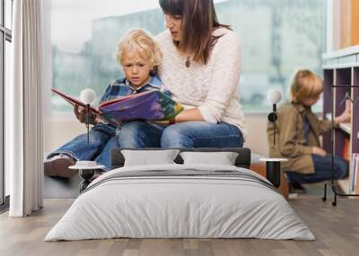 teacher with boy reading book in library Wall mural