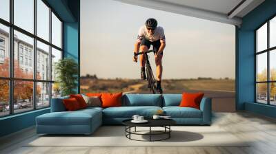 Happy road cyclist in protective helmet training outdoors Wall mural