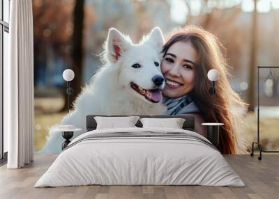 Young woman smiling and hugging her white dog with one blue eye in a park, capturing a joyful moment of companionship and affection. Wall mural