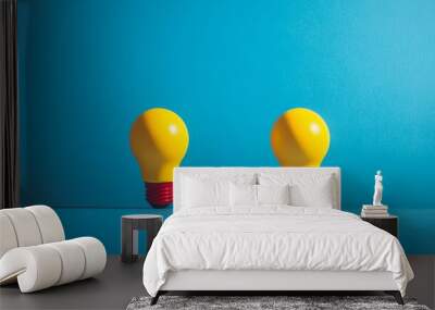 Two yellow light bulbs are on a blue background Wall mural