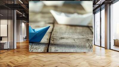 A blue paper boat leads a fleet of small white boats on a wooden table with a vintage effect. Wall mural