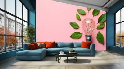 An eco-green energy concept bulb is displayed on a pink background with leaves on it. Wall mural