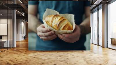 In closeup, a man is breaking a loaf of fresh bread on a dark background Wall mural