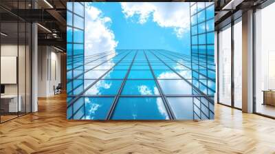 Looking up at a glass skyscraper with blue sky and clouds reflected in the windows Wall mural