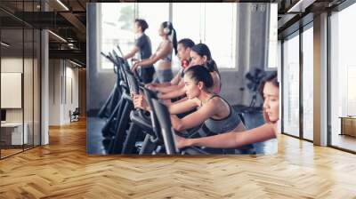 group friends working out on exercise bike and wearing sportswear in fitness or gym center, strength sporty and weight loss concept Wall mural