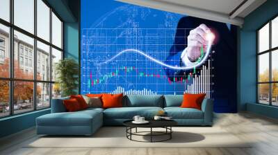 A man wearing a suit  his right hand poked a pencil on a fast-growing stock chart. Globe background and blurred lights Wall mural