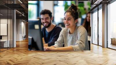 Happy young office colleagues collaborating and smiling working at computers in open plan workplace Wall mural