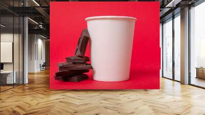 Closeup of white paper cup of hot chocolate and pieces of it o the red background Wall mural