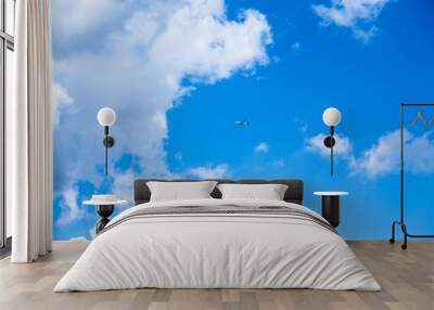 Cloudscape against a blue sky. The plane flies high above large white clouds. Travel on vacation with airlines. Wall mural