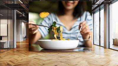 Woman eating delicious pasta in restaurant Wall mural