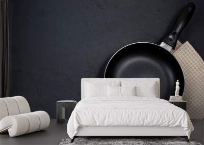 Empty black frying pan with kitchen towel on black table. Wall mural